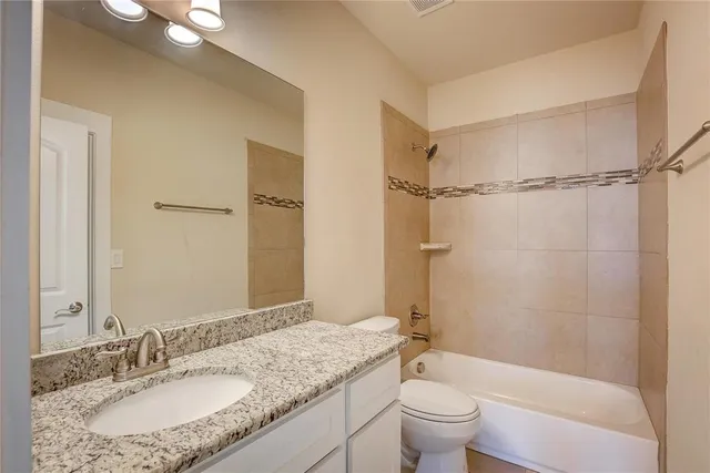 a bathroom with a granite countertop sink a toilet and shower