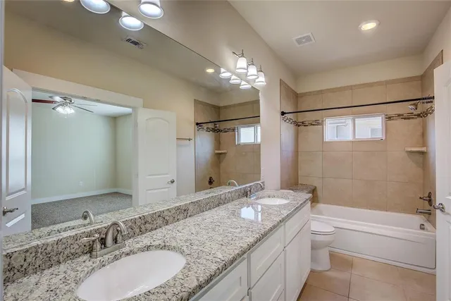 a bathroom with a granite countertop double vanity sink mirror double and bathtub