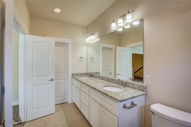 a bathroom with a granite countertop sink a toilet and a large mirror
