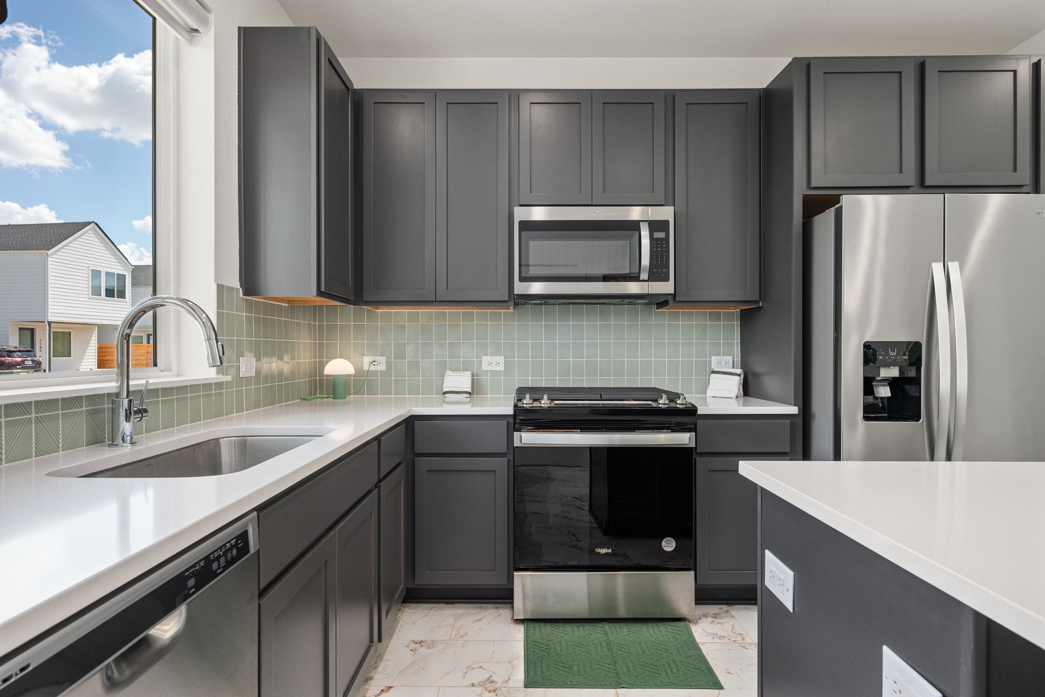 1190 Sarabeth Way Austin, TX 78721 - Photo 5 of 22 Streamlined cabinetry and sleek quartz countertops frame a modern culinary workspace designed for efficiency.