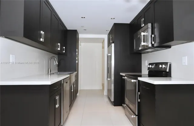 a kitchen with stainless steel appliances a sink a stove a refrigerator and cabinets