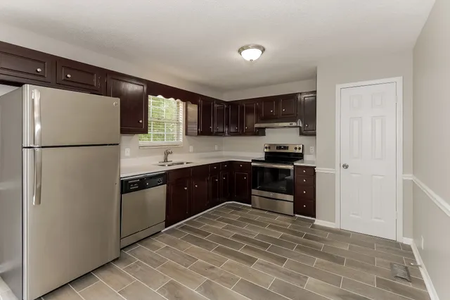 a kitchen with granite countertop a refrigerator stove top oven and sink