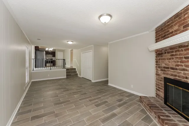 a view of a electric appliances in kitchen and an empty room with wooden floor
