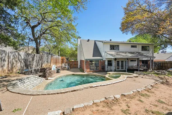 a view of a house with a large tree and wooden fence