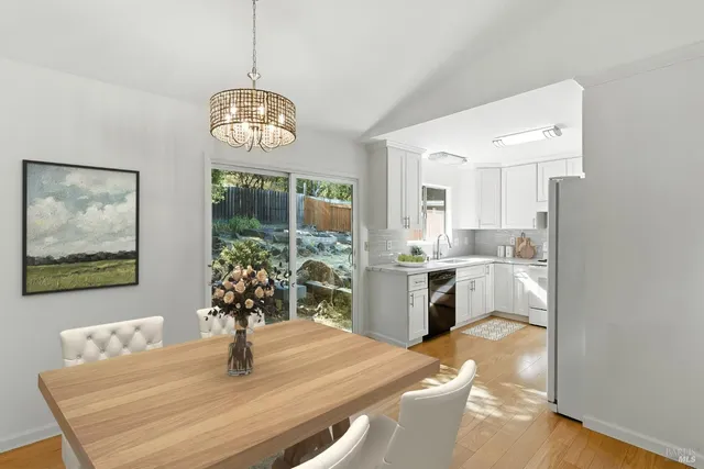 a dining room with wooden floor a chandelier a wooden table and chairs