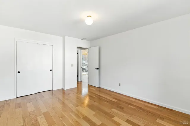 a view of an empty room with wooden floor fireplace and a window