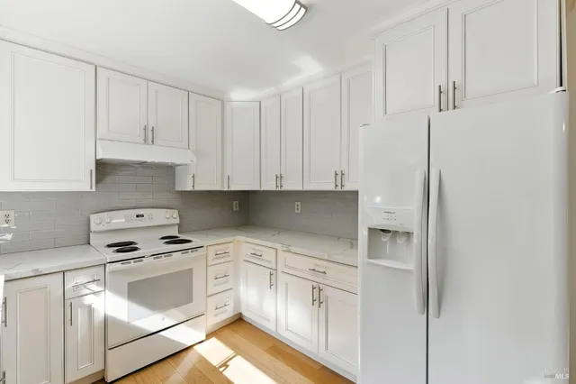 a open kitchen with granite countertop a stove top oven a sink and dishwasher with wooden floor