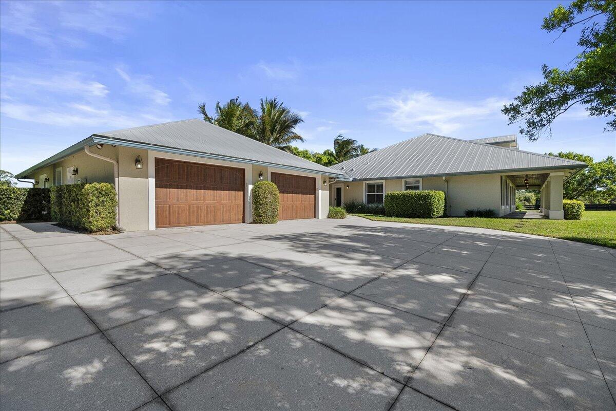 10975 Randolph Siding Road Jupiter, FL 33478 - Photo 6 of 97 a front view of a house with a yard and garage