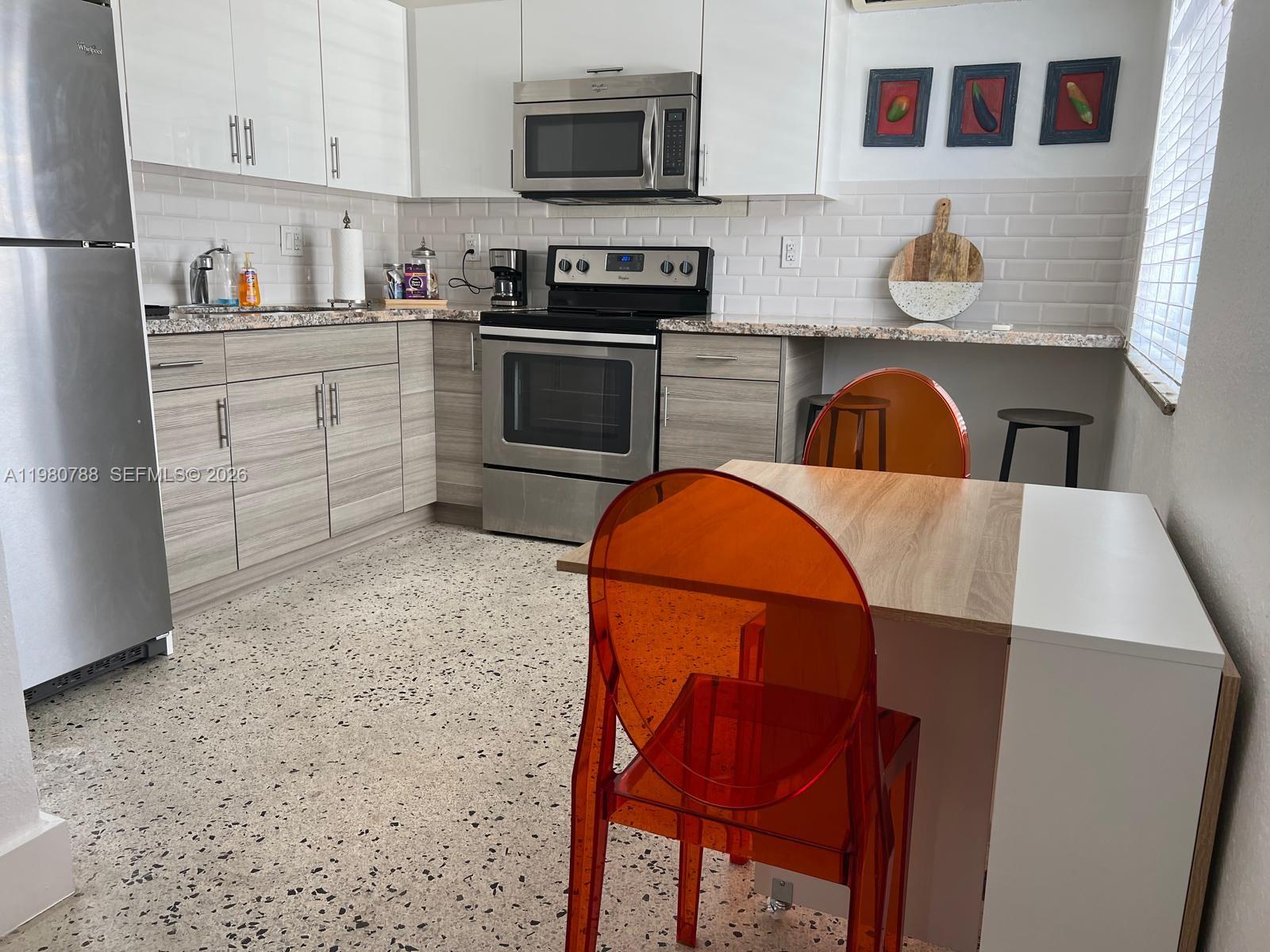 1736 Southwest 3rd Street, Unit 1 Miami, FL 33135 - Photo 3 of 6 a kitchen with stainless steel appliances granite countertop a stove a sink dishwasher and a refrigerator with wooden cabinets