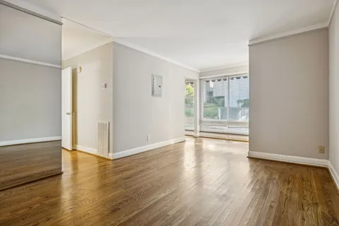 an empty room with wooden floor and windows