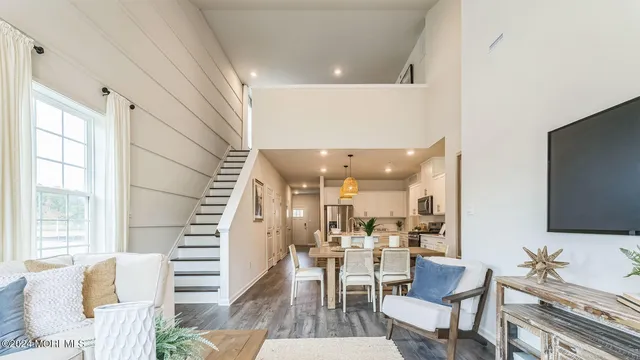a living room with couches and a flat screen tv with kitchen view