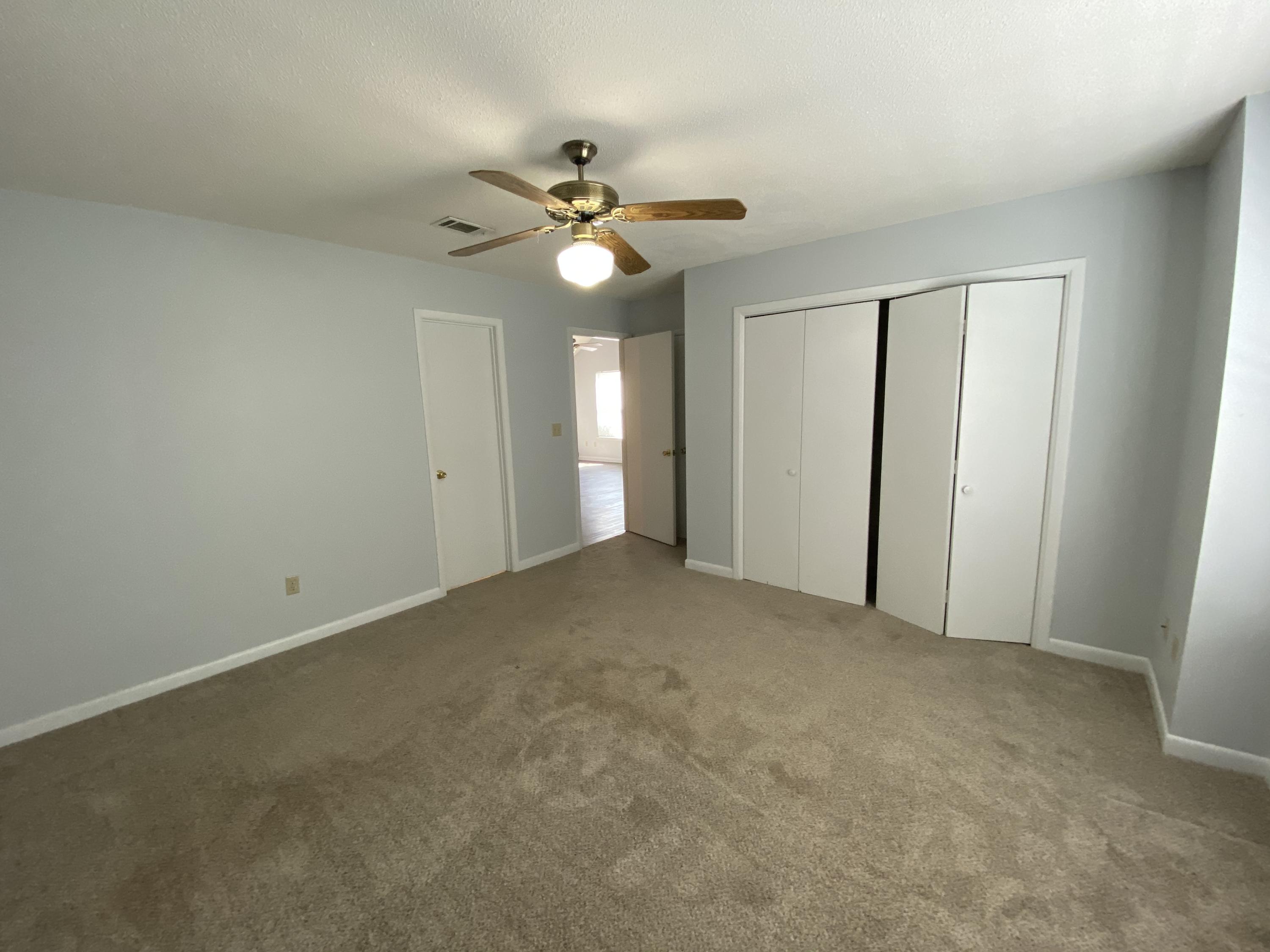 169 Wright Circle Niceville, FL 32578 - Photo 13 of 27 an empty room with a chandelier fan and windows