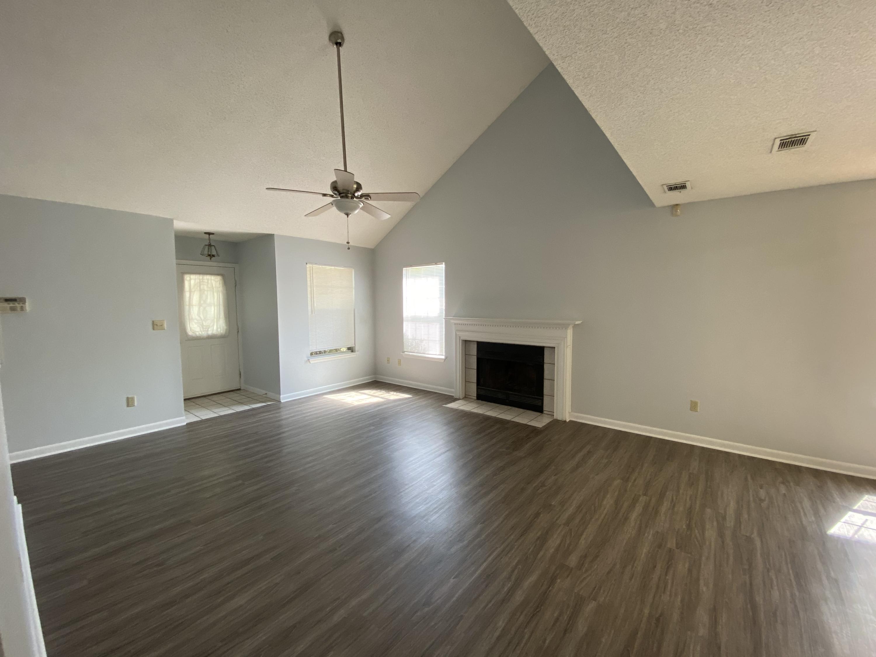169 Wright Circle Niceville, FL 32578 - Photo 2 of 27 an empty room with wooden floor fireplace and windows