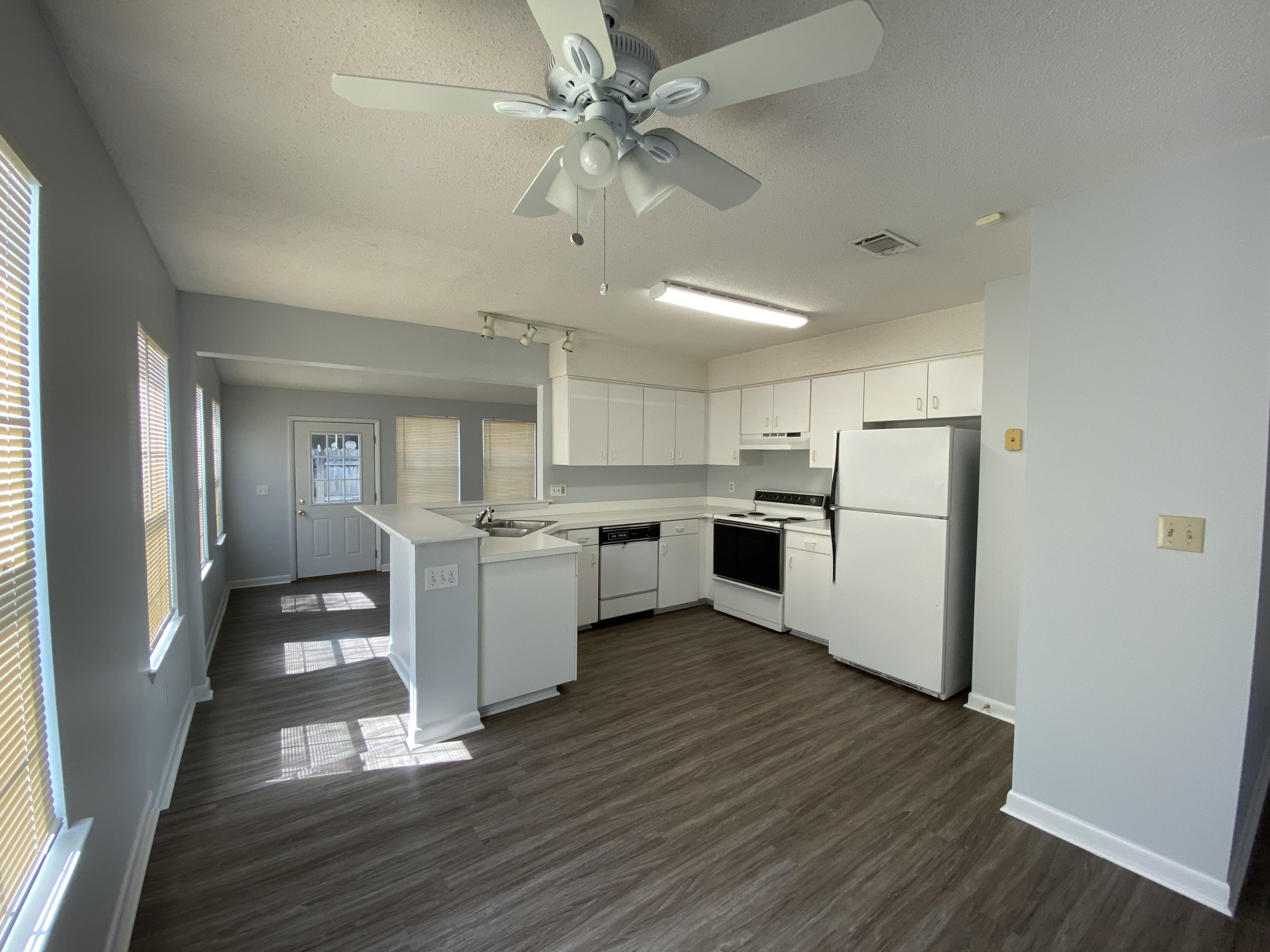 169 Wright Circle Niceville, FL 32578 - Photo 5 of 27 a kitchen with a refrigerator a stove top oven a sink dishwasher and a dining table with wooden floor