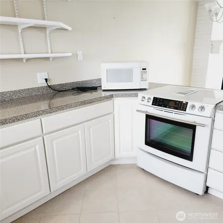 a kitchen with granite countertop white cabinets and white appliances