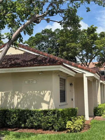a front view of a house with a yard and a large tree