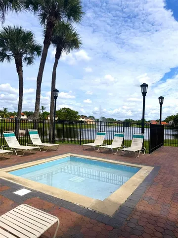 a view of a swimming pool with a lawn chairs and palm tree
