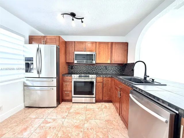 a kitchen with granite countertop a refrigerator stove and sink