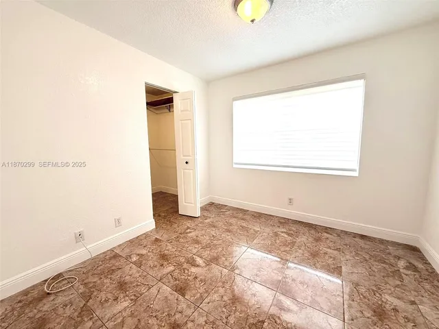a view of an empty room with window and closet area