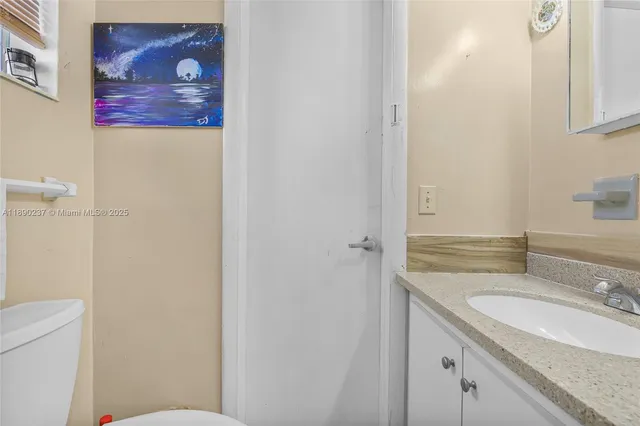 a bathroom with a granite countertop sink mirror vanity and toilet