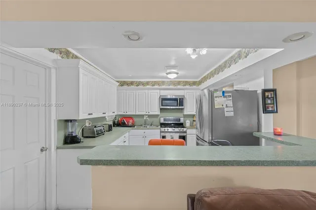 a kitchen with stainless steel appliances granite countertop a sink refrigerator and cabinets