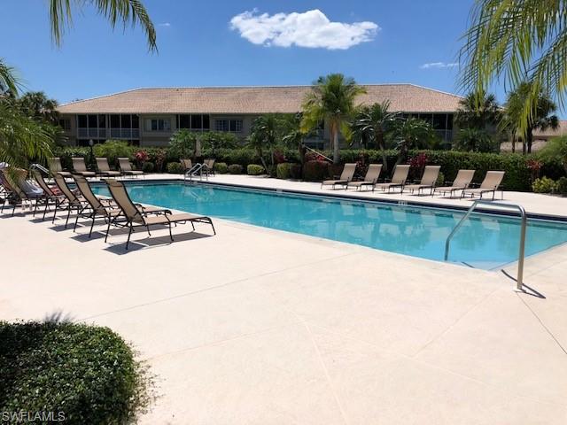 9009 Michael Circle, Unit 1110 Naples, FL 34113 - Photo 22 of 27 a view of a swimming pool with a table and chairs under an umbrella