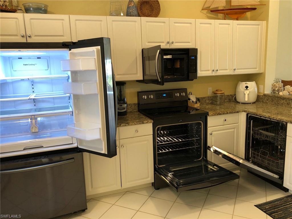 9009 Michael Circle, Unit 1110 Naples, FL 34113 - Photo 8 of 27 a kitchen with granite countertop a stove and a refrigerator