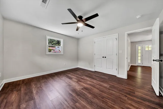 a view of empty room with wooden floor and ceiling fan