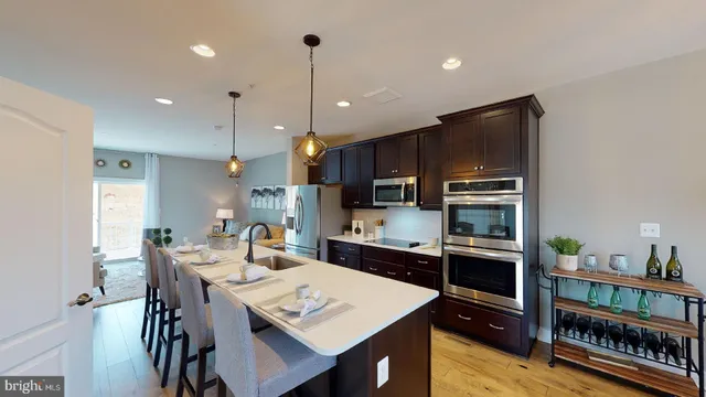 a kitchen with stainless steel appliances kitchen island granite countertop a refrigerator a stove a kitchen island a dining table and chairs