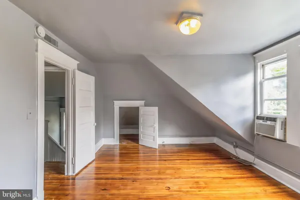 a view of an empty room with window and wooden floor