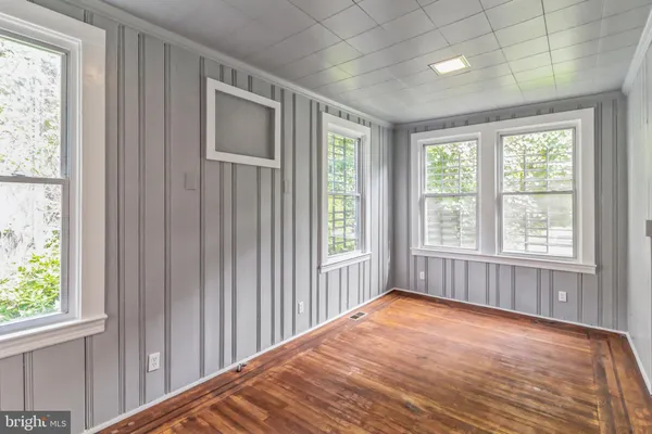 an empty room with wooden floor and windows