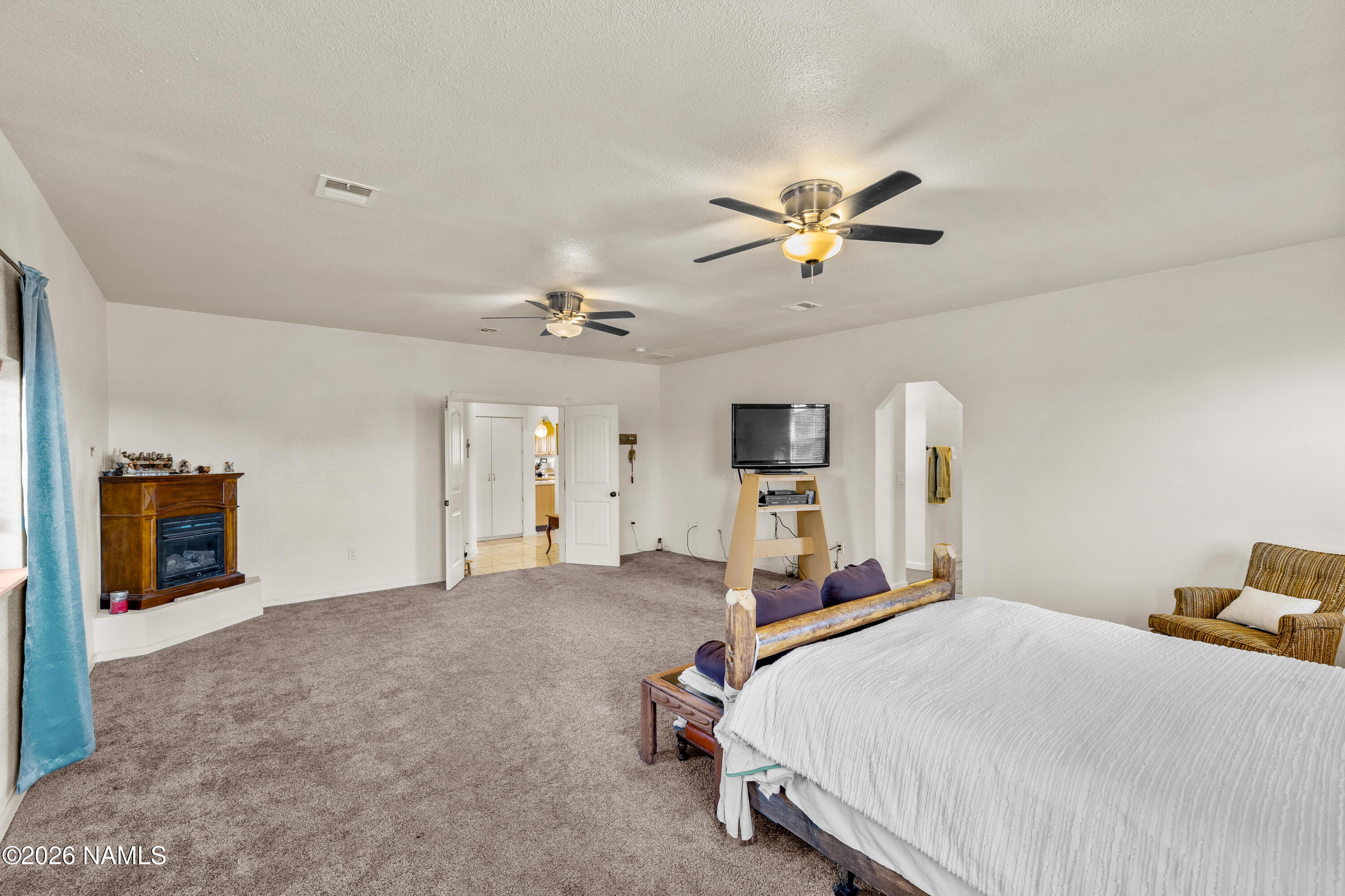 8187 Cassity Trail Williams, AZ 86046 - Photo 19 of 50 a bedroom with a bed ceiling fan and a fireplace
