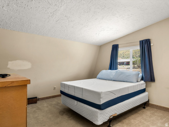 85 B Street, Unit 22 St. Charles, ID 83272 - Photo 28 of 35 Carpeted room with a textured ceiling and a window featuring blinds and dark blue curtains