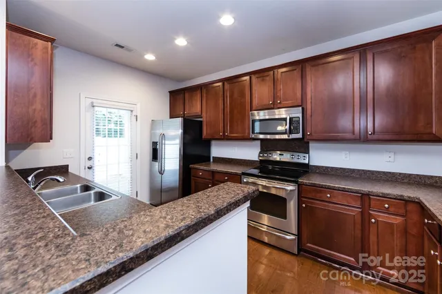 a kitchen with kitchen island granite countertop wooden cabinets stainless steel appliances and a counter space
