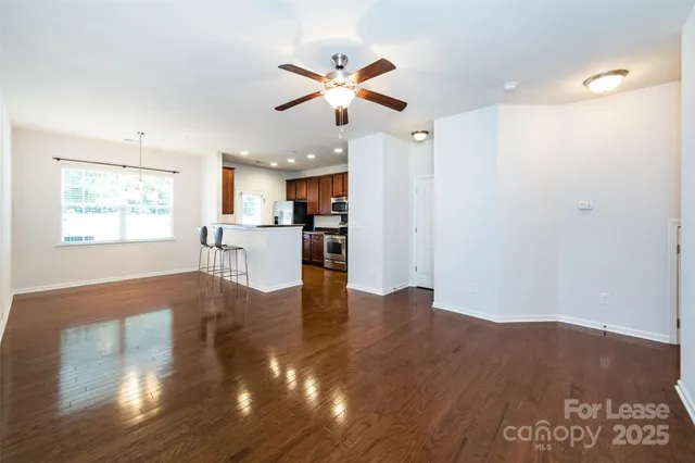 an empty room with wooden floor and a ceiling fan