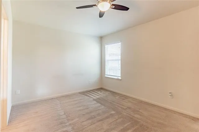an empty room with a window and a fan