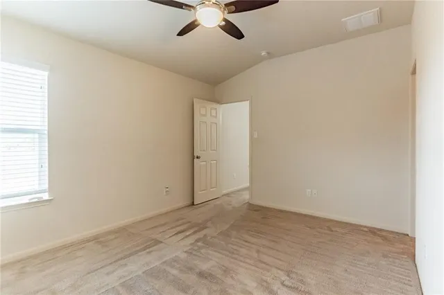 an empty room with a window and ceiling fan