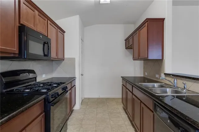 a kitchen with stainless steel appliances granite countertop a sink stove and microwave