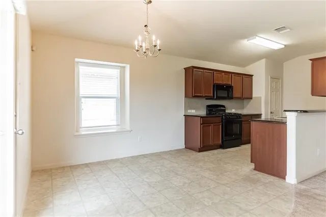 a kitchen with kitchen island granite countertop a stove top oven a sink dishwasher a dining table and chairs with wooden floor