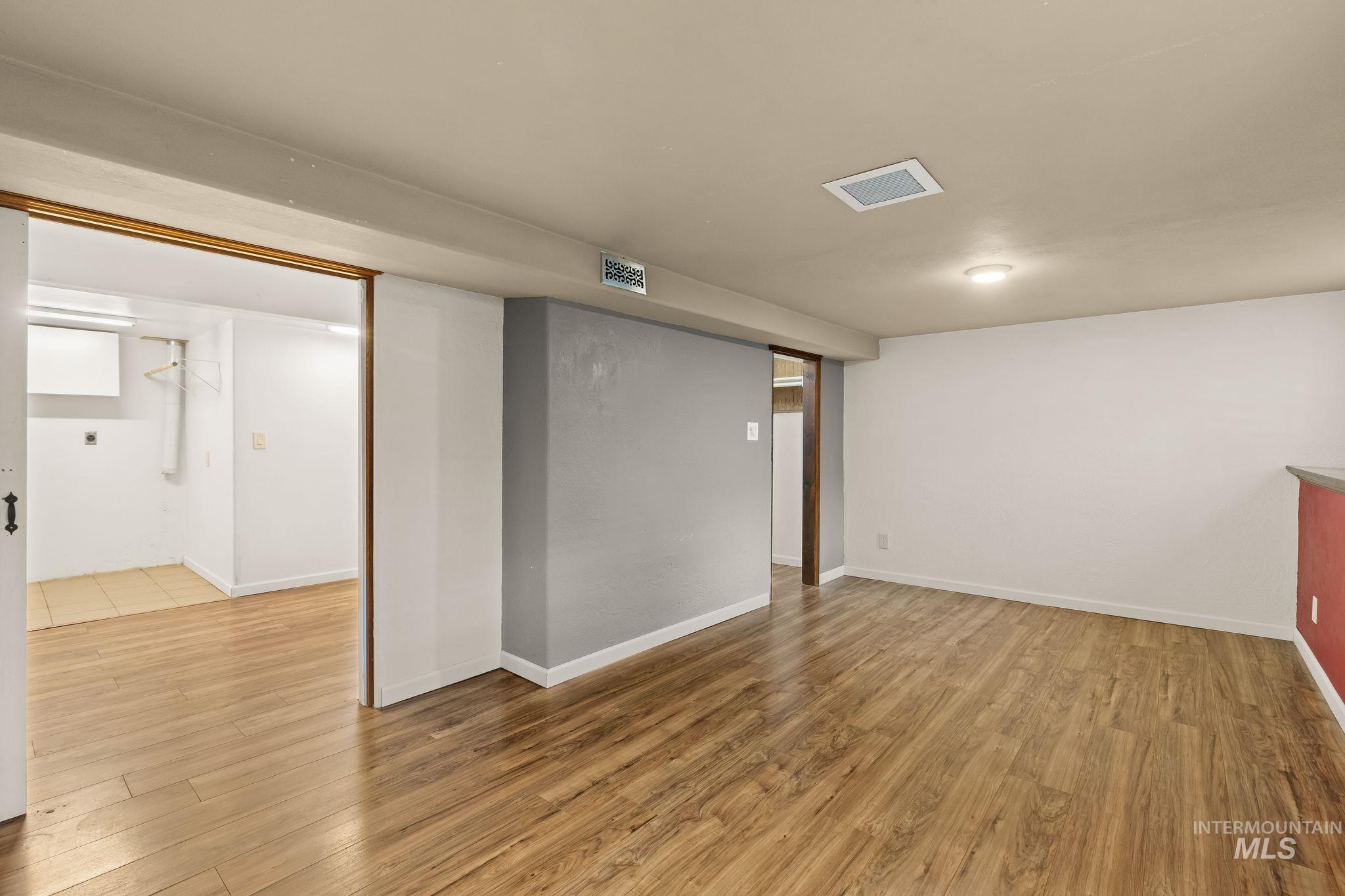 928 3rd Street Clarkston, WA 99403 - Photo 29 of 44 Spacious room featuring wood-finish flooring, recessed lighting, a red accent wall, and a separate utility area with tile flooring