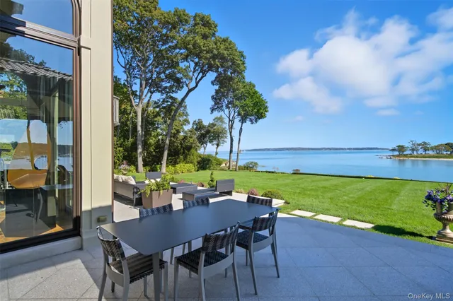 a view of a patio with couches table and chairs under an umbrella and garden