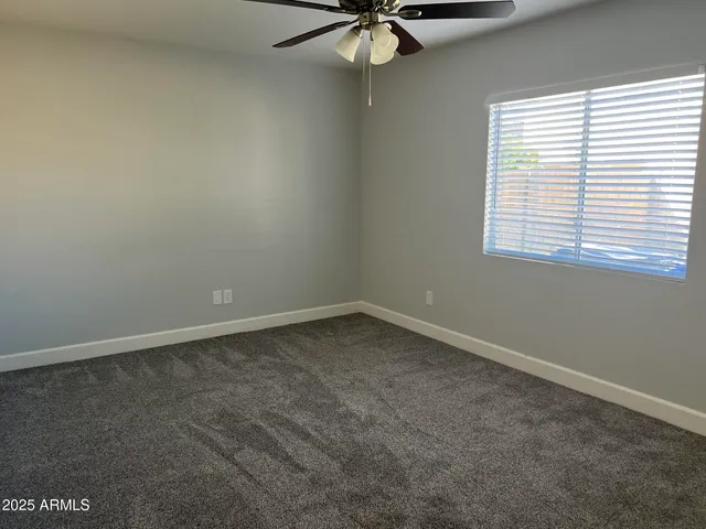 an empty room with a window and a fan