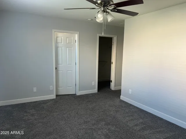 an empty room with closet and a chandelier fan