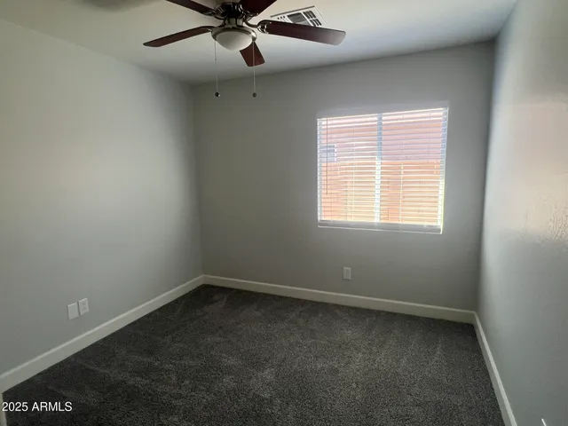 an empty room with a window and a fan
