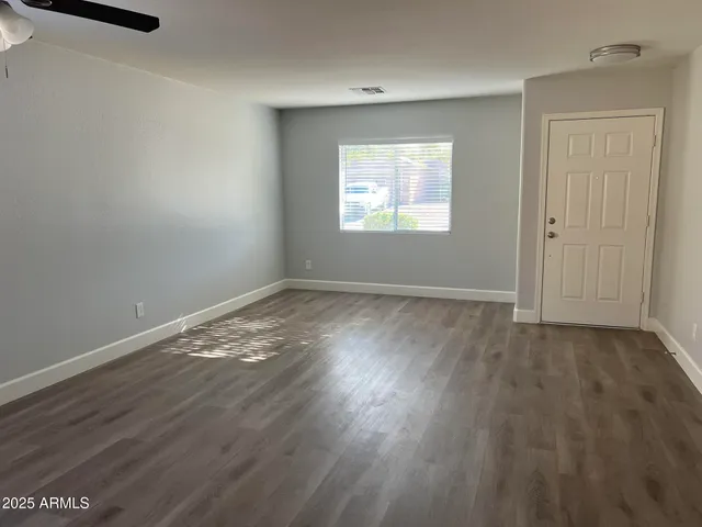 a view of an empty room with wooden floor and a window