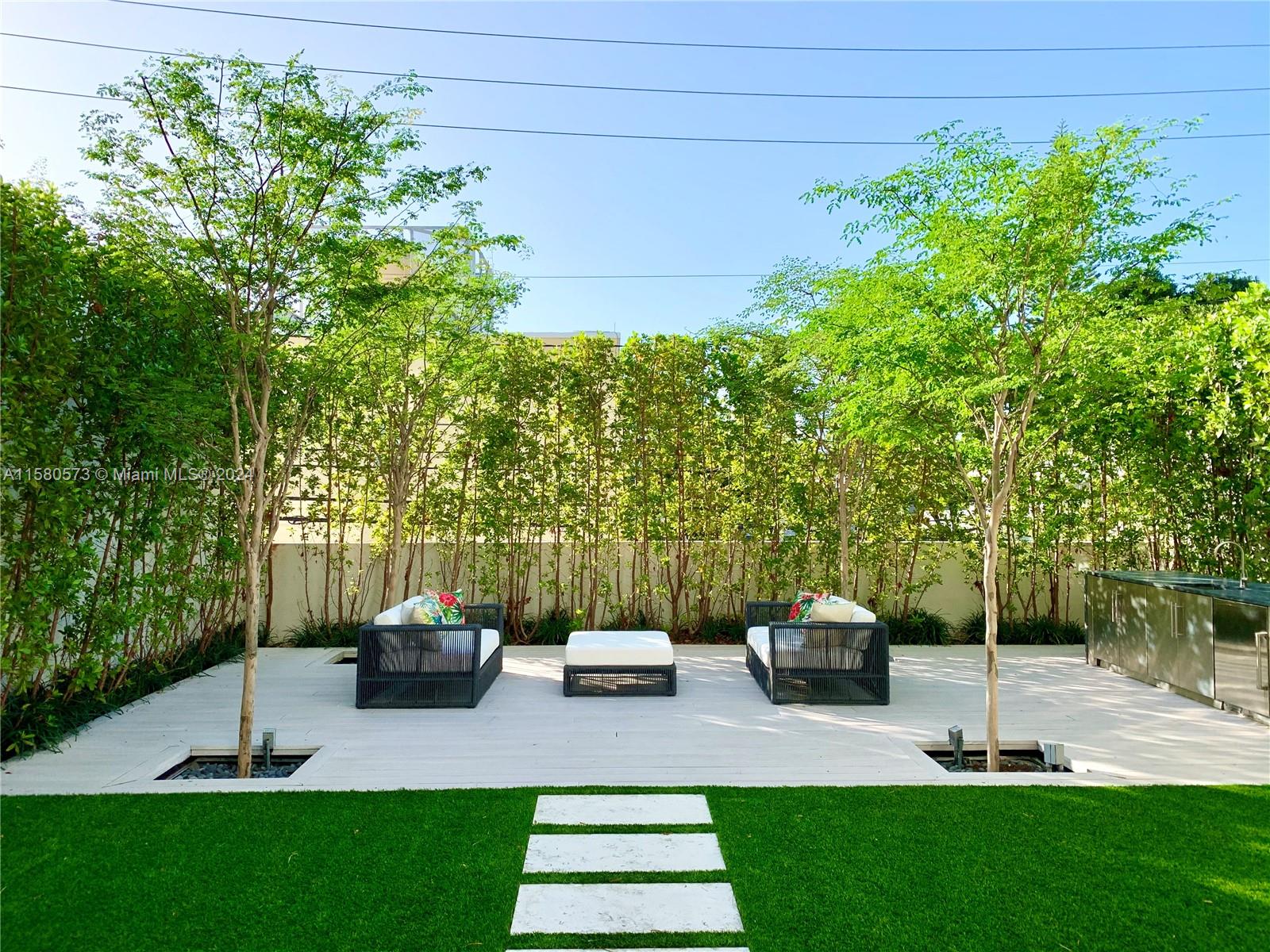 a view of a patio with couches plants and large trees