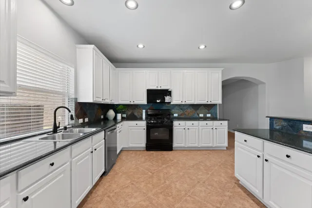a kitchen with granite countertop white cabinets and stainless steel appliances