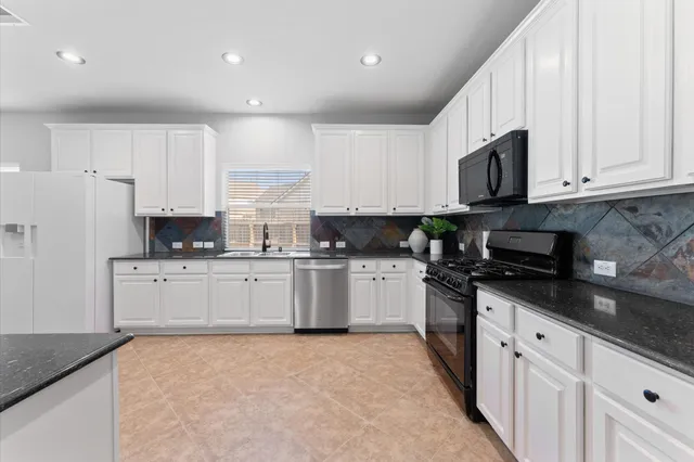 a kitchen with granite countertop white cabinets sink and stainless steel appliances
