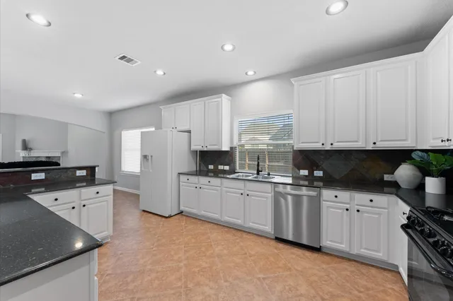 a kitchen with white cabinets and appliances