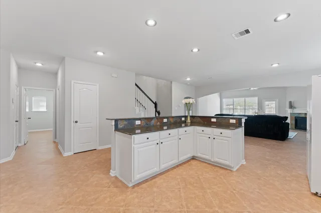 a kitchen with granite countertop a sink and white cabinets